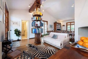 Ein geräumiges Wohnzimmer mit einer großen Bücherwand, einem Sofa, einem Couchtisch und einem Zebra-Teppich.