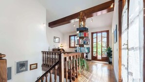 Una scala in legno con ringhiera, una libreria e una porta che dà su una stanza luminosa e piena di luce naturale.