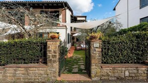 Un cancello in pietra che dà accesso a una casa con un vialetto lastricato e un giardino.