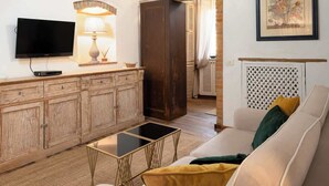 Sala de estar com sofá, televisão, armário de madeira e lareira.