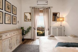 Una camera da letto con un letto, una cassettiera, uno specchio, una lampada e vista all'esterno.