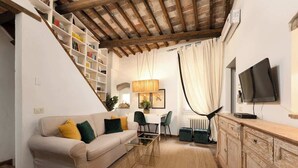 Uma sala de estar com sofá, mesa de centro, televisão e escada com estantes.