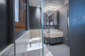 Un bagno moderno con doccia vetrata, lavabo in marmo e uno specchio grande.