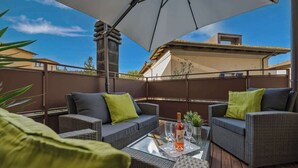An outdoor patio with wicker furniture, a glass table, and a bottle of wine. - Il toscano - Nuovo con terrazza in centro a Greve (Greve in Chianti)