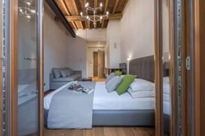Ein Schlafzimmer mit einem Bett, einem Schlafsofa, einem Nachttisch, einer Lampe und einer Holzzahlende.