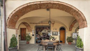 An outdoor patio with a round table and chairs, an arched brick ceiling, and potted plants. - Casa Falorni, 1 - Raffaello - Bilocale (Greve in Chianti)