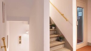 A staircase with a handrail, a door with a sign, and a tiled floor. - Casa Falorni, 1 - Raffaello - Bilocale (Greve in Chianti)