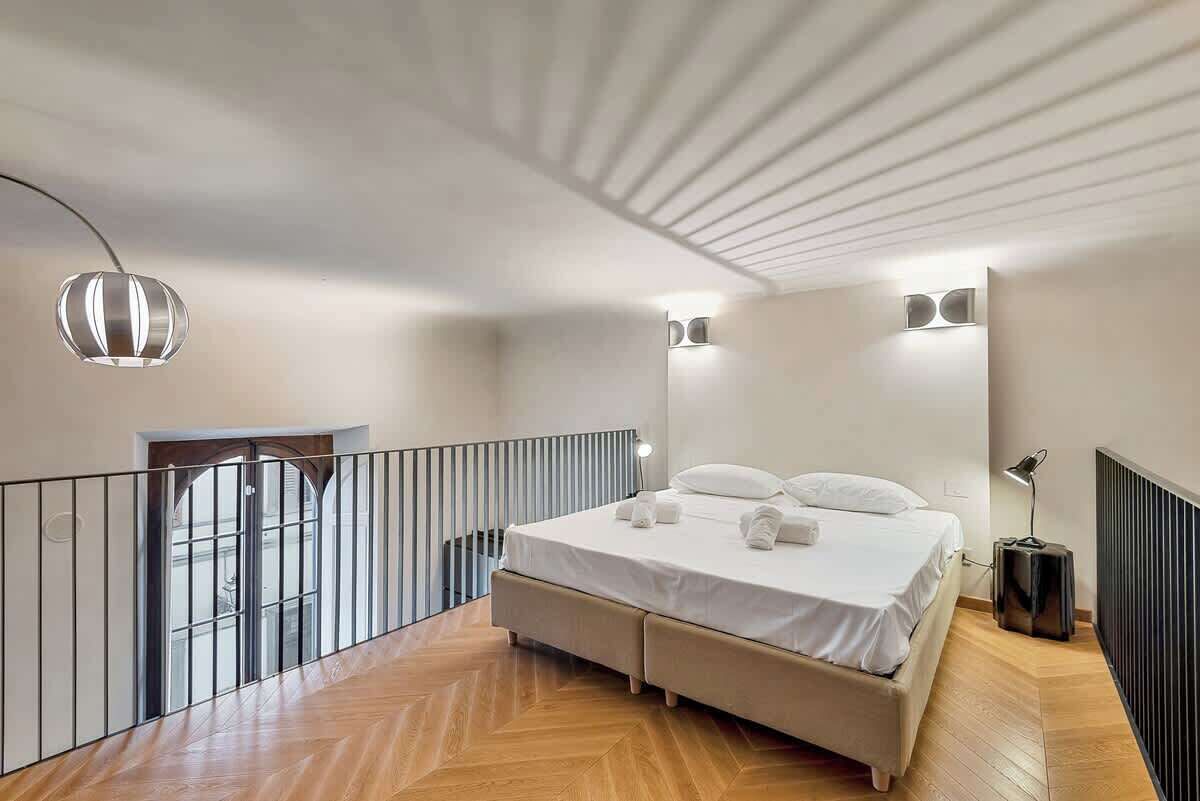 Ein modernes Schlafzimmer mit Bett, einer Pendelleuchte und Blick ins Freie.