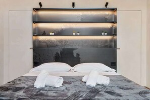 A bed with a headboard, pillows, and rolled towels. - Maison - Luxury and Design Three-Room Apartment (Firenze)