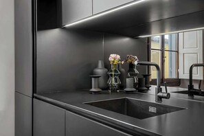 A modern kitchen with a black countertop, a sink, and a mirror reflecting the room. - Maison - Luxury and Design Three-Room Apartment (Firenze)