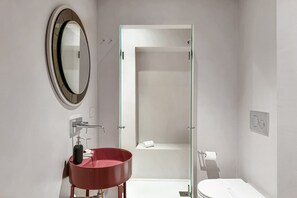 A bathroom with a round mirror, a red sink, a glass shower enclosure, and a toilet. - Maison - Luxury and Design Three-Room Apartment (Firenze)