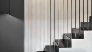 Eine moderne Treppe mit minimalistischem Design, bestehend aus dunklen Stufen und vertikalen Linien.