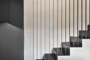 A modern staircase with a minimalist design, featuring a series of dark steps and vertical lines. - Maison - Luxury and Design Three-Room Apartment (Firenze)