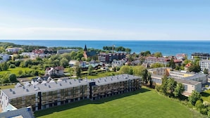 A residential area with a large building featuring multiple balconies, surrounded by greenery and a view of the sea. - Elegant Studio with Terrace, Close to the Sea by Noclegi Renters (Ustronie Morskie)