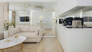 A modern kitchen with a built-in oven, a dining area with a white table and sofa, and a living room with a beige sofa and a coffee table. - Elegant Studio with Terrace, Close to the Sea by Noclegi Renters (Ustronie Morskie)