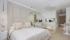 A modern bedroom with a large bed, bedside tables, a mirror, and a small seating area. - Elegant Studio with Terrace, Close to the Sea by Noclegi Renters (Ustronie Morskie)