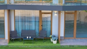 A modern building with a glass facade, a balcony with two chairs and a table, and a potted plant. - Elegant Studio with Terrace, Close to the Sea by Noclegi Renters (Ustronie Morskie)