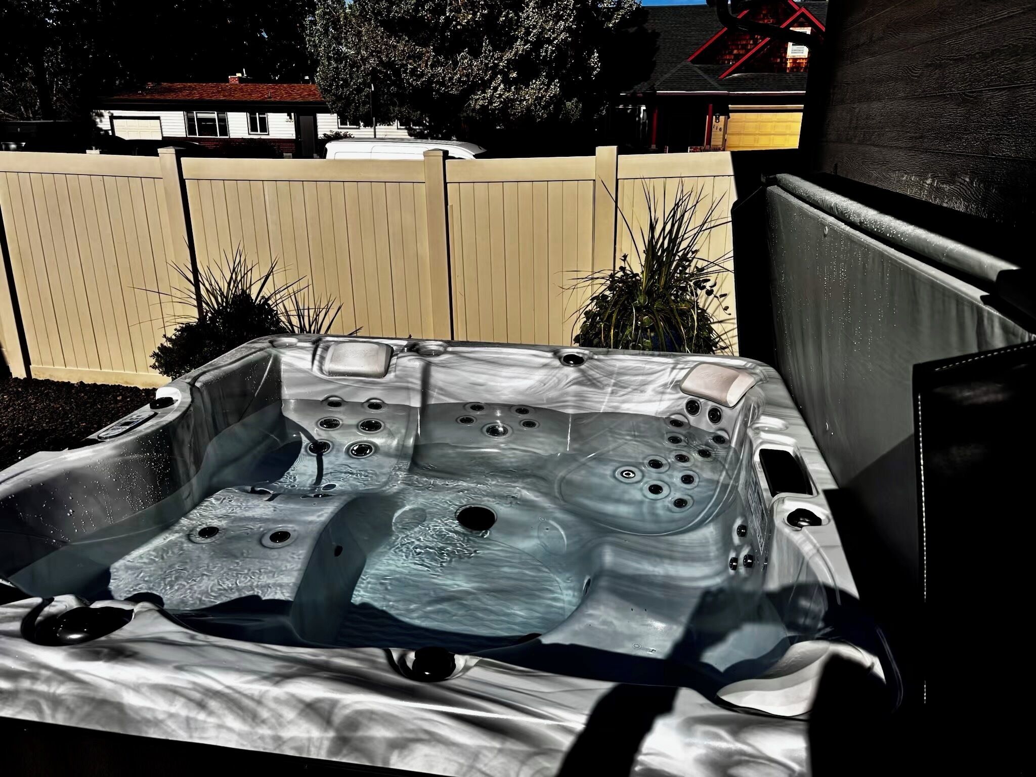 A hot tub in a vehicle, surrounded by a fence and plants.