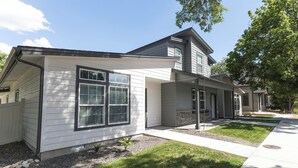 A modern two-story house with a covered porch, a small garden, and a well-maintained lawn. - This 3BR/2BA retreat. North End Haven | Steps from Parks, Trails & Local Favorites Walking distance to Hyde Park  and Camel’s back park | Close to Boise White Water park and E Bikes For Rent it simple at this peaceful and centrally-located place. (Boise)