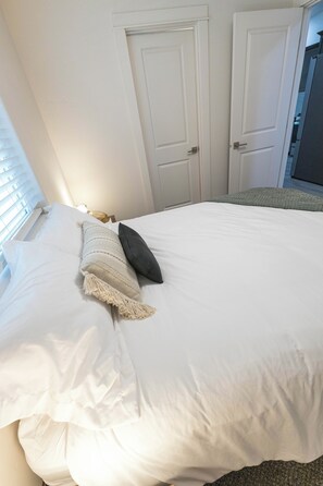 Una camera da letto con un letto, due porte e una finestra con tende.