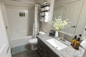 A bathroom with a bathtub, toilet, sink, and shower curtain. - This 3BR/2BA retreat. North End Haven | Steps from Parks, Trails & Local Favorites Walking distance to Hyde Park  and Camel’s back park | Close to Boise White Water park and E Bikes For Rent it simple at this peaceful and centrally-located place. (Boise)
