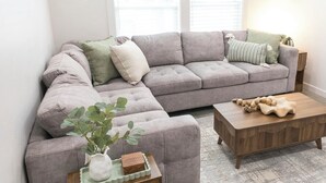 A living room with a grey sectional sofa, a wooden coffee table, a small side table with a plant, and a patterned rug. - This 3BR/2BA retreat. North End Haven | Steps from Parks, Trails & Local Favorites Walking distance to Hyde Park  and Camel’s back park | Close to Boise White Water park and E Bikes For Rent it simple at this peaceful and centrally-located place. (Boise)
