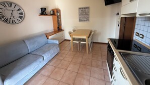 Uma cozinha compacta com uma mesa de madeira, um sofá, um relógio de parede e um mapa.