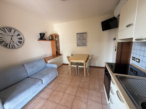 Eine kleine Küche mit einem Holztisch, einer Couch, einer Wanduhr und einer Karte.