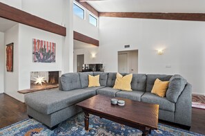 Ein modernes Wohnzimmer mit einer Eckcouch, einem Holztisch und einem gemusterten Teppich.