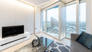 Ein modernes Wohnzimmer mit einem Flachbildfernseher, einem Glastisch und einem Sofa.