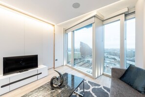 A modern living room with a flat-screen TV, a glass coffee table, and a sofa. - Stylish 2 Bed Flat in the Heart of Olympic Park (London)