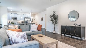 Una sala moderna con un sofá, una mesa de centro y una zona de comedor con una cocina al fondo.