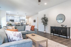 Una sala moderna con un sofá, una mesa de centro y una zona de comedor con una cocina al fondo.