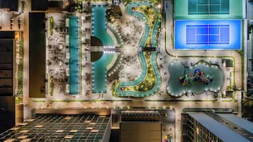 Un espace piscine aménagé sur le toit, avec un bassin sinueux, des coins salon et un court de tennis.