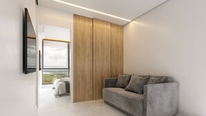 A modern living room with a grey sofa, wooden panel wall, and a large window offering a view.