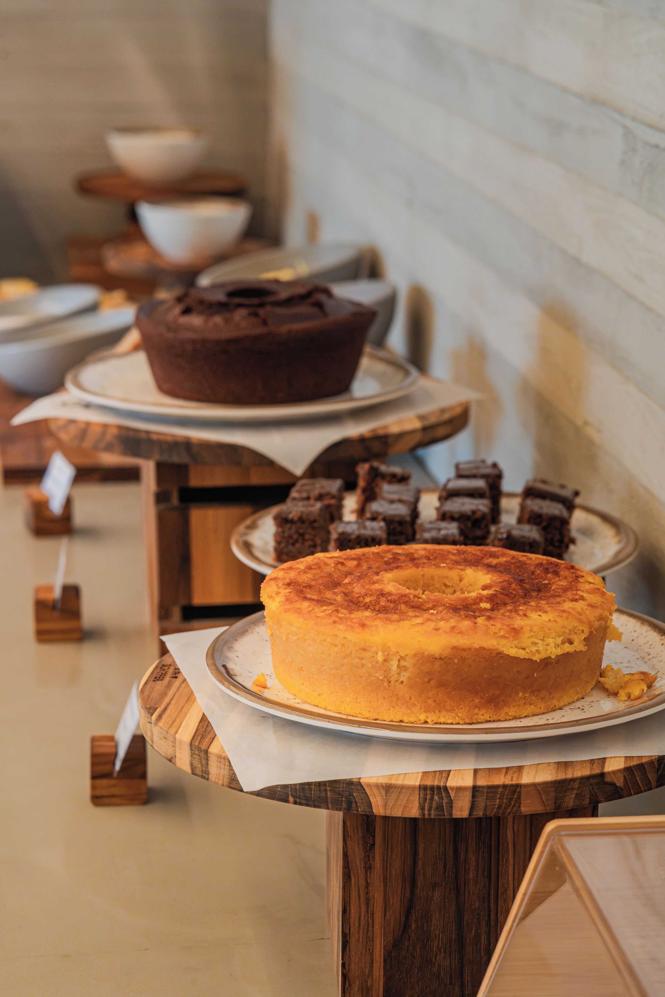 A dessert display with cakes and brownies on a wooden table.