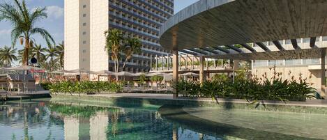 A hotel with a large pool, palm trees, and modern architecture.