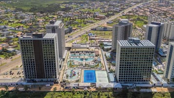 Hotel moderno com um pátio central que inclui uma piscina, cercado por vegetação exuberante e áreas residenciais.