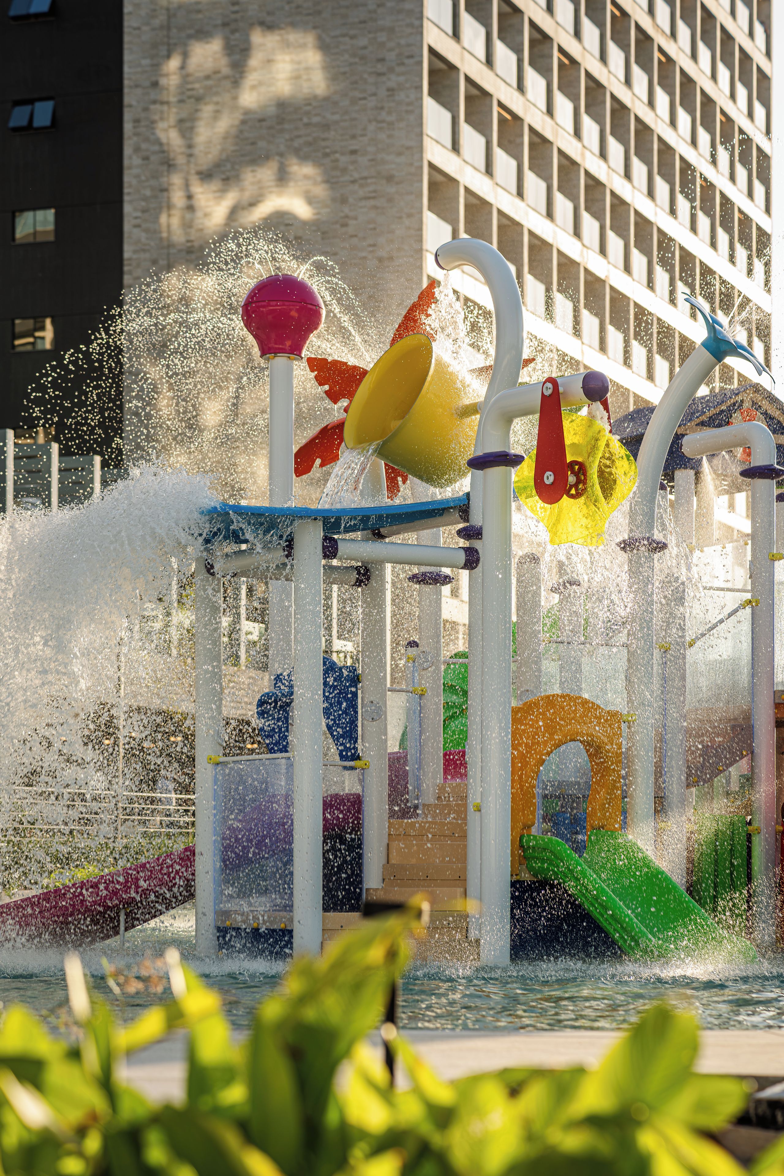 Een buitenspeelplaats met waterattracties, zoals fonteinen en glijbanen.