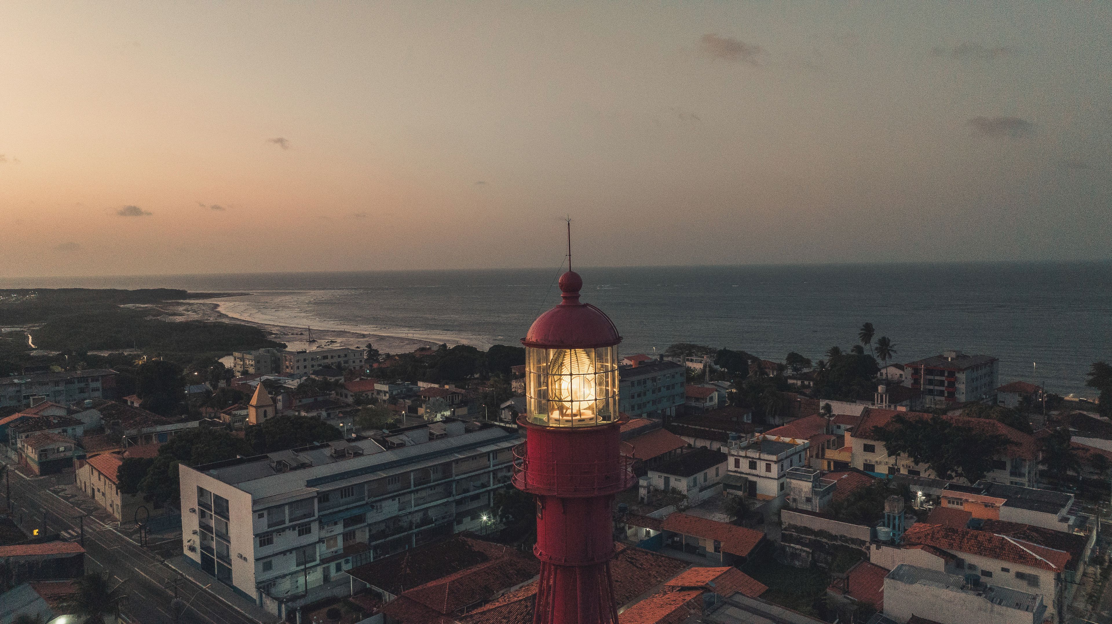 Un pueblo costero con un faro destacado, edificios y una playa.