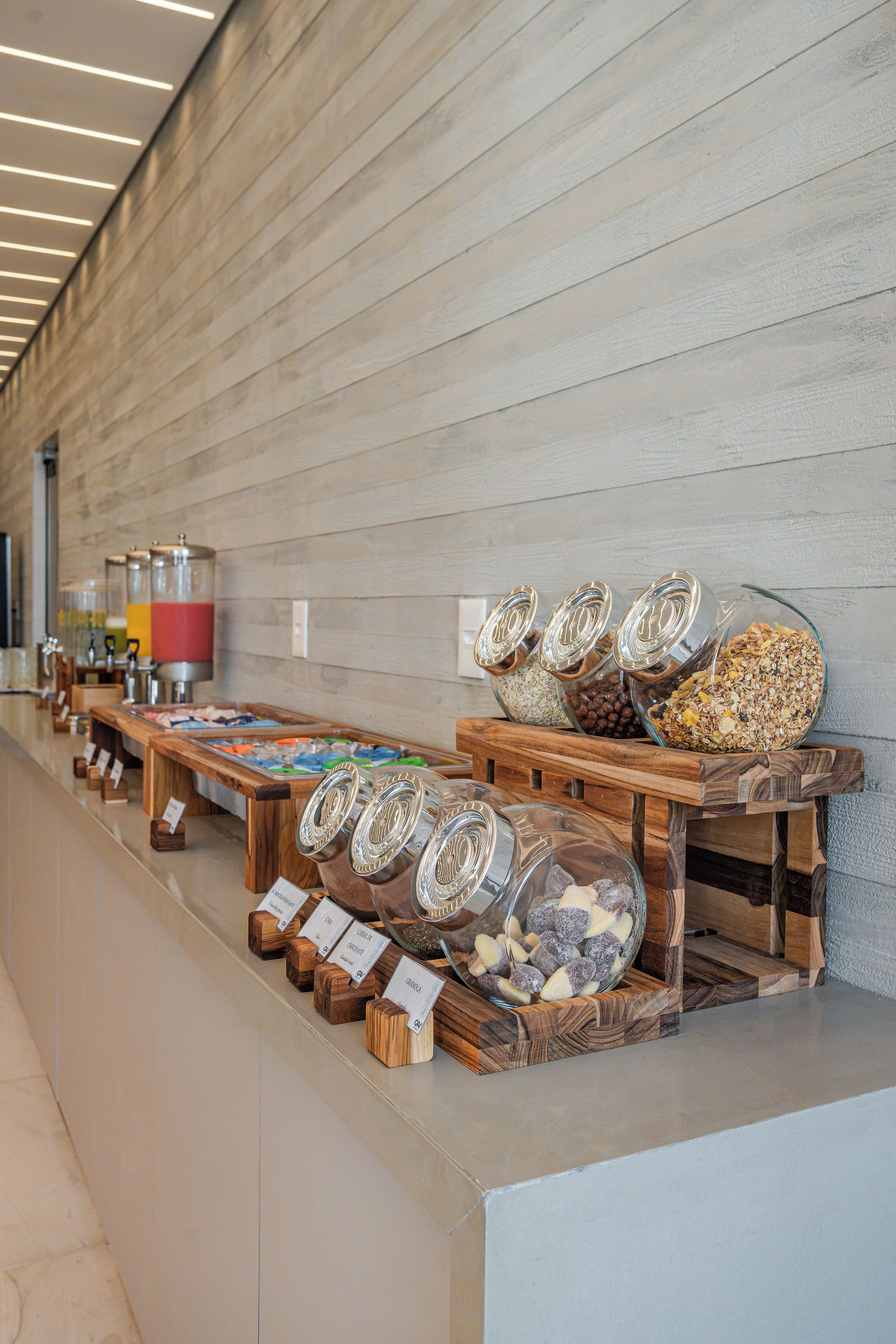 Een presentatie van eten en drinken met diverse hapjes en drankjes in glazen containers en op houten plankjes.