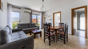 Una sala de estar moderna con sofá, mesa de comedor, sillas y una araña.