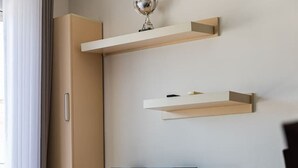 Una habitación moderna con una televisión sobre un mueble bajo, un armario y un trofeo en una estantería.