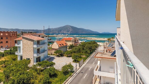Une vue sur la côte, avec des bâtiments, un port de plaisance et une montagne en arrière-plan.