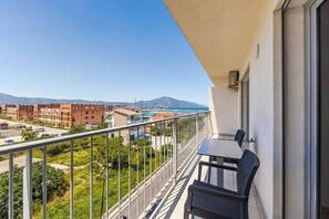 Un balcon avec une table et des chaises, donnant sur une marina et des immeubles.