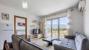 A modern living room with a sofa, TV, and balcony with a view.