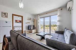 Un salon moderne avec un canapé, un téléviseur et un balcon offrant une vue agréable.