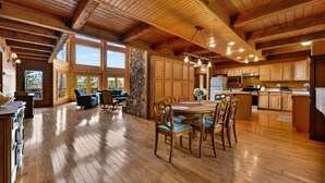 Un interior espacioso de madera con zona de comedor, cocina y pared de piedra.