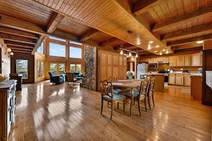 A spacious wooden interior with a dining area, kitchen, and stone wall.