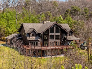 A large log cabin with a prominent porch and multiple windows.